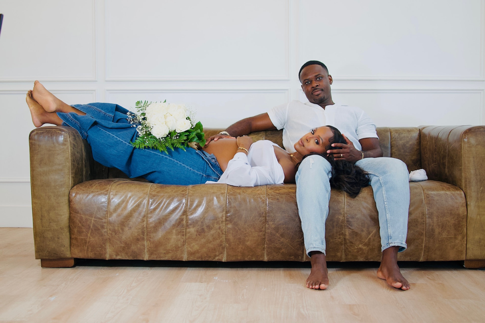 Couple photographed together on a leather sofa during a Cerene Studios session
